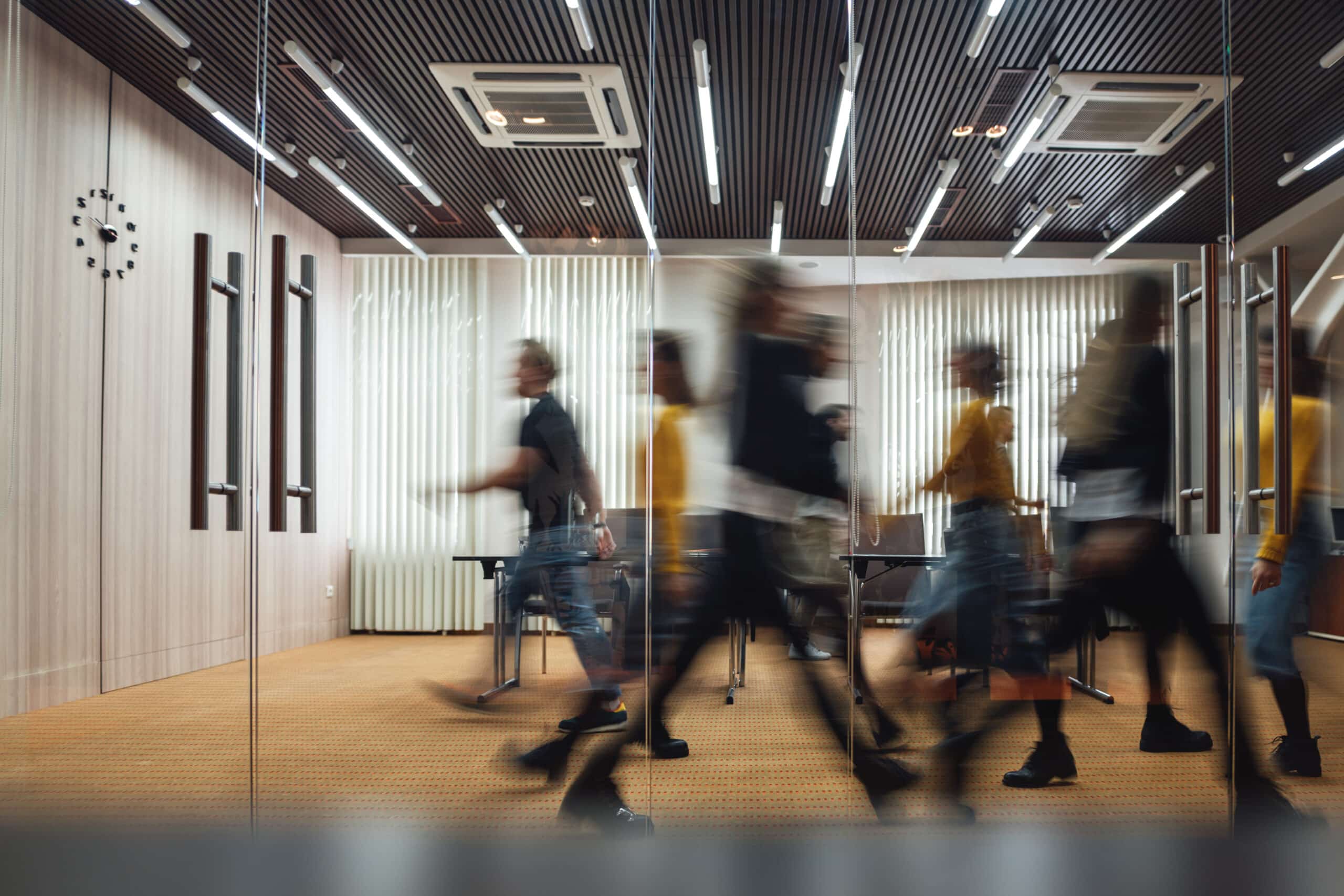 Group of office employees at coworking center. Business people walking at modern open space. Motion blur concept